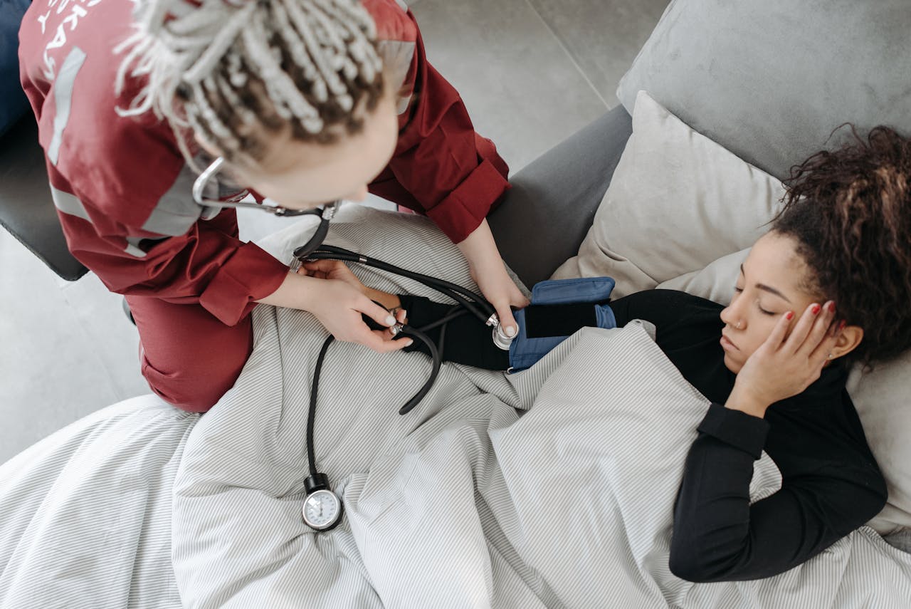 Paramedic measuring patients blood pressure indoors, illustrating home healthcare assistance.